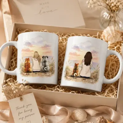 Personalized dog mom mug displayed beside an elegant gift box with ribbon, flowers and seashells